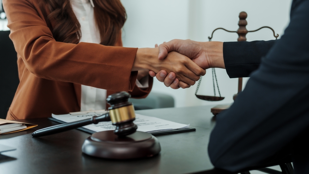A group of female lawyers of Asian descent—Japanese and Chinese—are shaking hands, exchanging bribes in the form of dollars after winning a lawsuit. They are shown extorting money from their clients through legal cases.