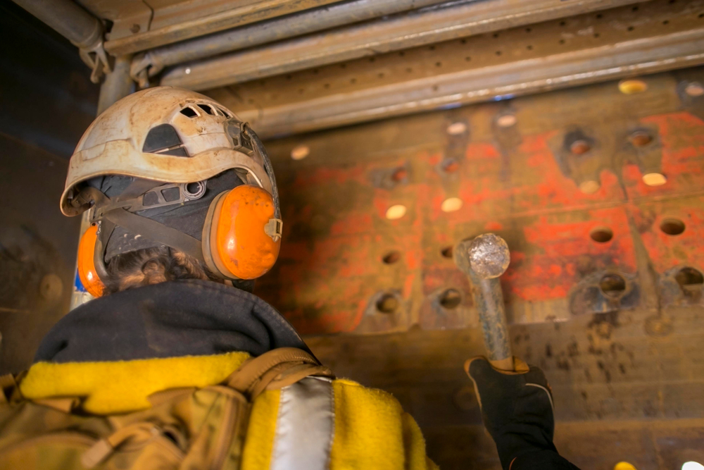 Employee with earmuffs protecting against workplace noise hazards