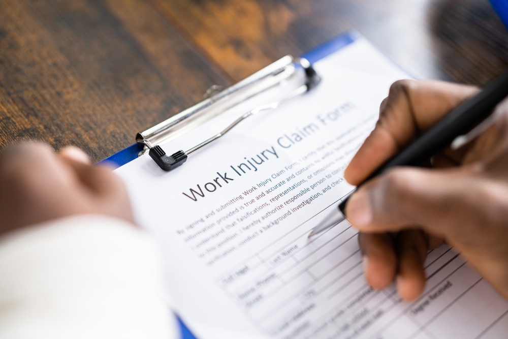 Person completing a work injury claim form on a clipboard